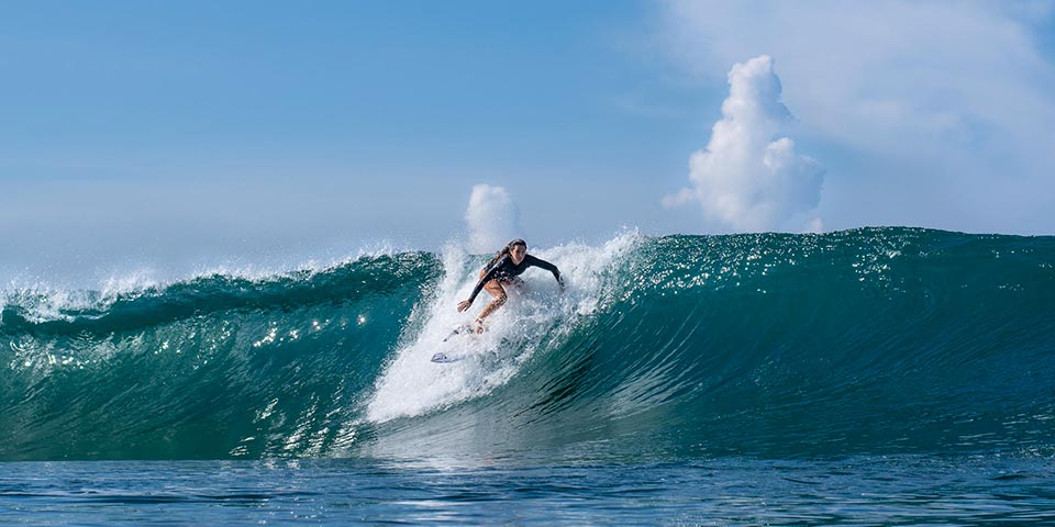 Sardinia surf girl on a beautiful emerald wave