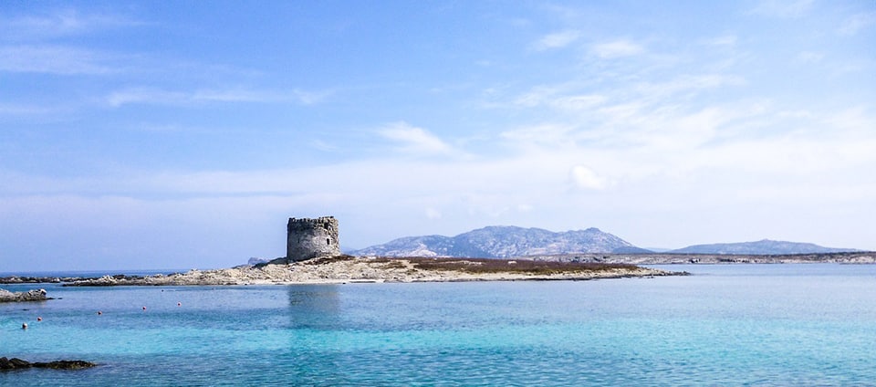 Il mare cristallino della Pelosa con la sua iconica torre e l'isola dell'Asinara sullo sfondo